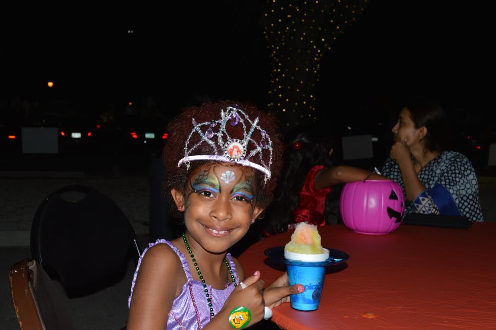 Girl with purple dress and Little Mermaid-themed crown shows snow cone